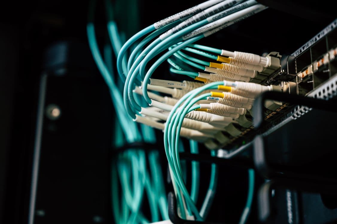 Técnico insertando módulo SFP transceptor en puerto de switch de red en datacenter, mostrando el proceso de instalación de transceptores compatibles recodificados en equipos Cisco Catalyst con fibra óptica monomodo conectada