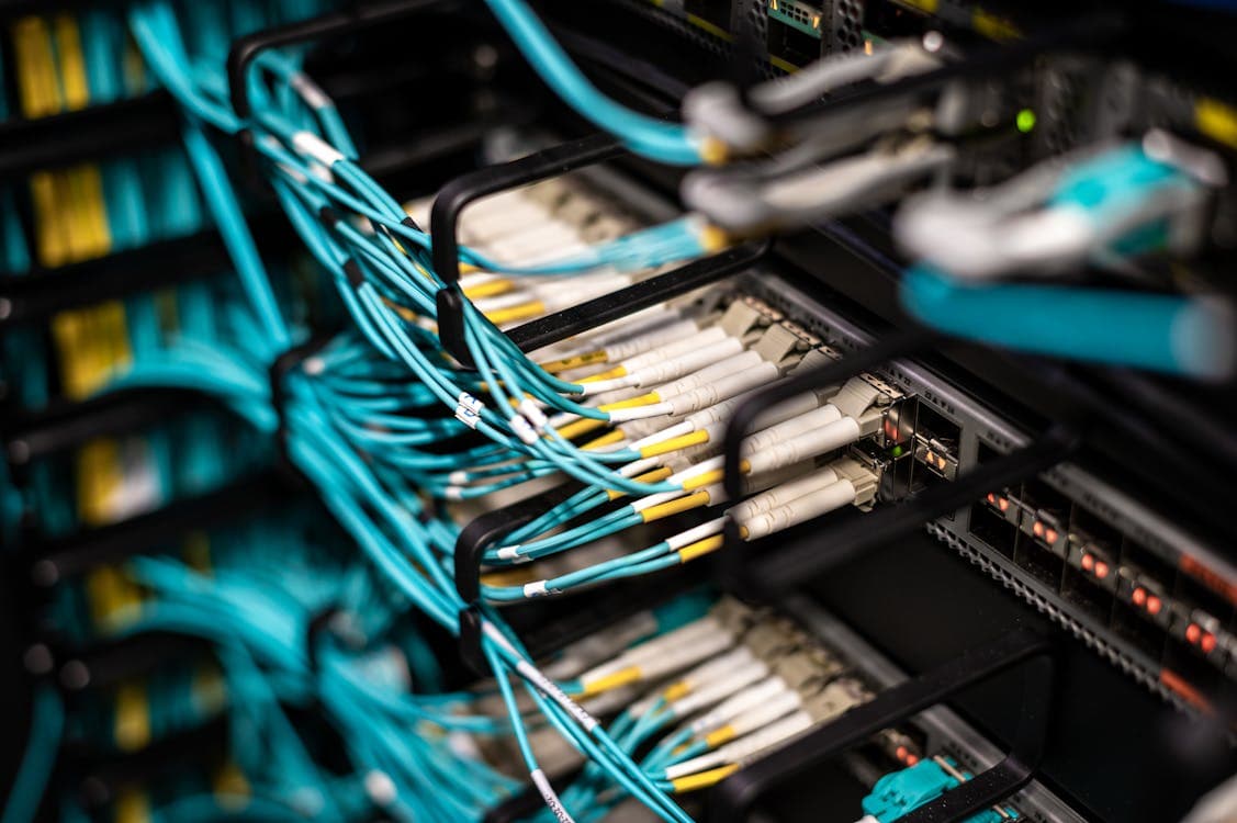 Switches de datacenter en rack con múltiples puertos QSFP+ conectados con cables de fibra óptica en arquitectura spine-leaf, donde cada módulo 40G transporta el tráfico agregado de múltiples servidores en la infraestructura de red empresarial