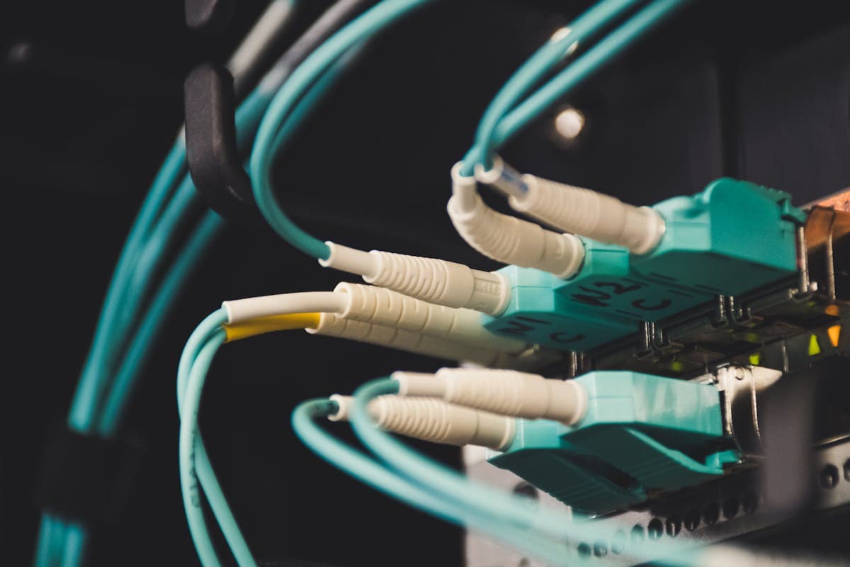 Vista detallada de cables de fibra óptica conectados a puertos de un servidor en sala de comunicaciones, con múltiples conectores LC de distintos colores que ilustran la diferencia entre fibra monomodo y multimodo
