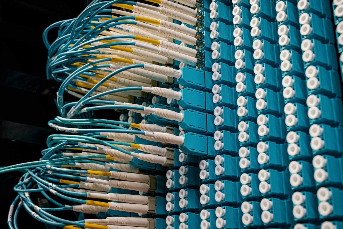 Cables de fibra óptica azules conectados a un patch panel en un datacenter, mostrando la organización de los conectores LC dúplex y la gestión del cableado estructurado de fibra